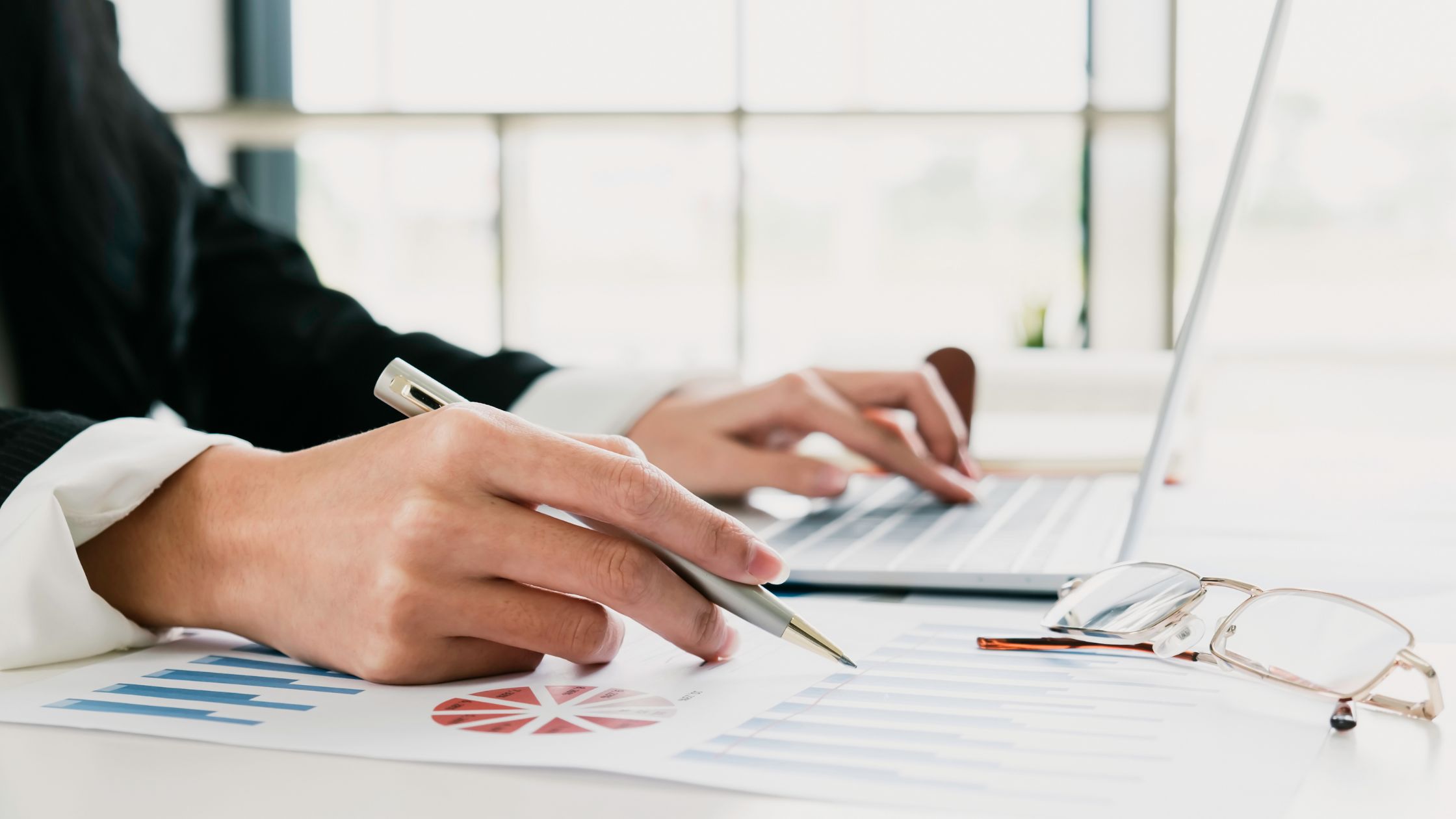 Profissional analisando gráficos financeiros e custos em laptop, representando otimização de custos na AWS.